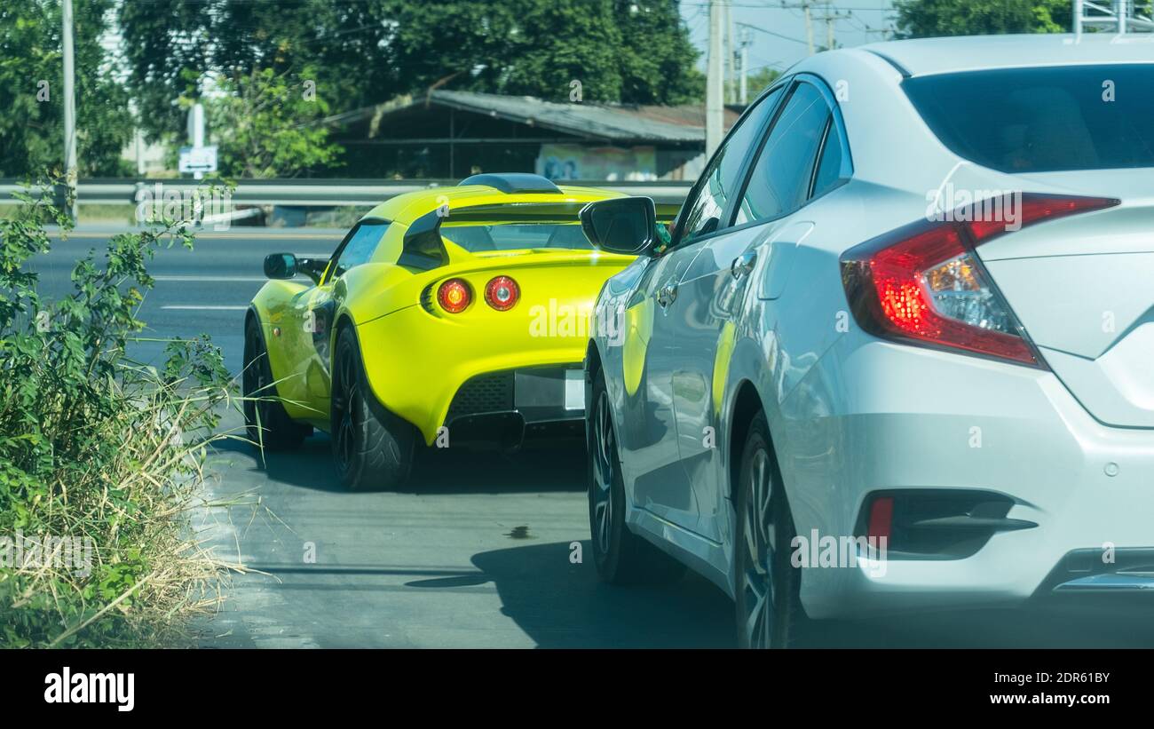 Gelbes Sportwagen und gewöhnliches graues Auto auf der Straße.16:9 Stil Stockfoto
