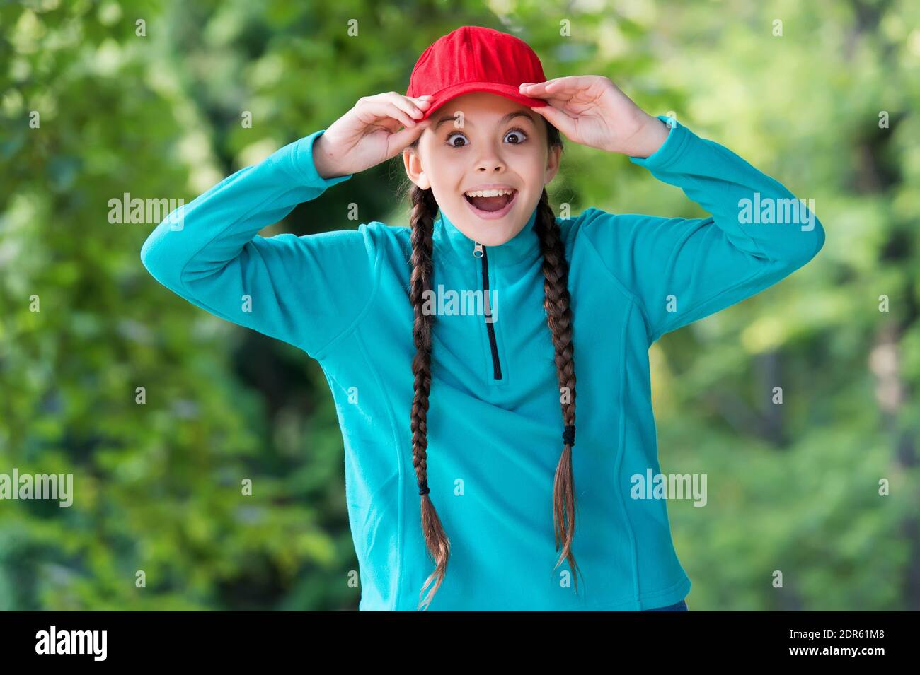Überrascht Mädchen halten Mund Augen weit offen Befestigung stilvolle Kappe mit Mode-Look in lässigen Stil natürliche Landschaft, Hipster. Stockfoto