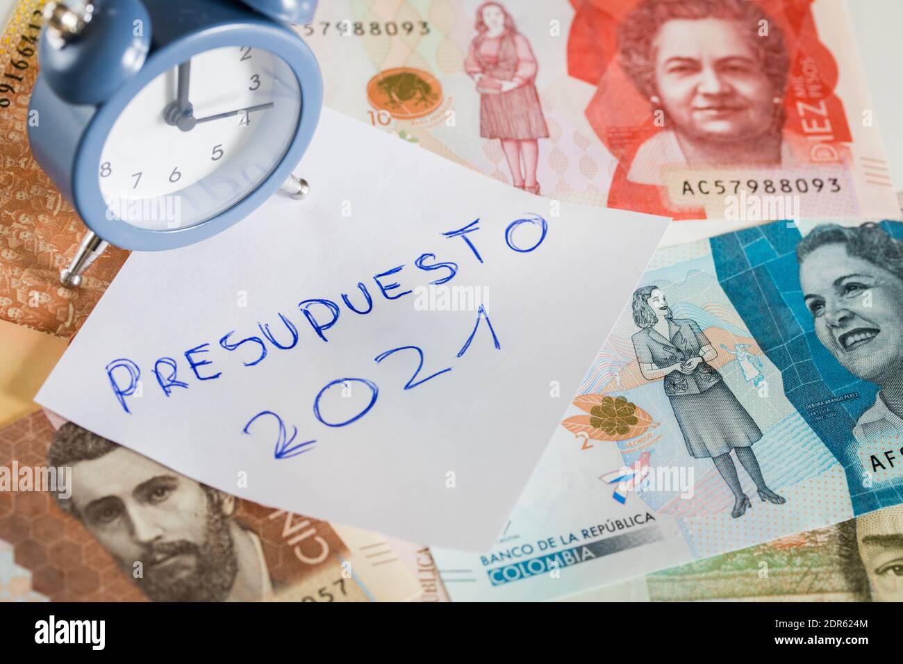 Handschriftliche Inschrift auf einem Blatt Papier in spanischer Sprache 'Presupuesto 2021', die den Haushalt im neuen Jahr bezeichnet. Kolumbianisches Geld und der Alarm-Block Stockfoto