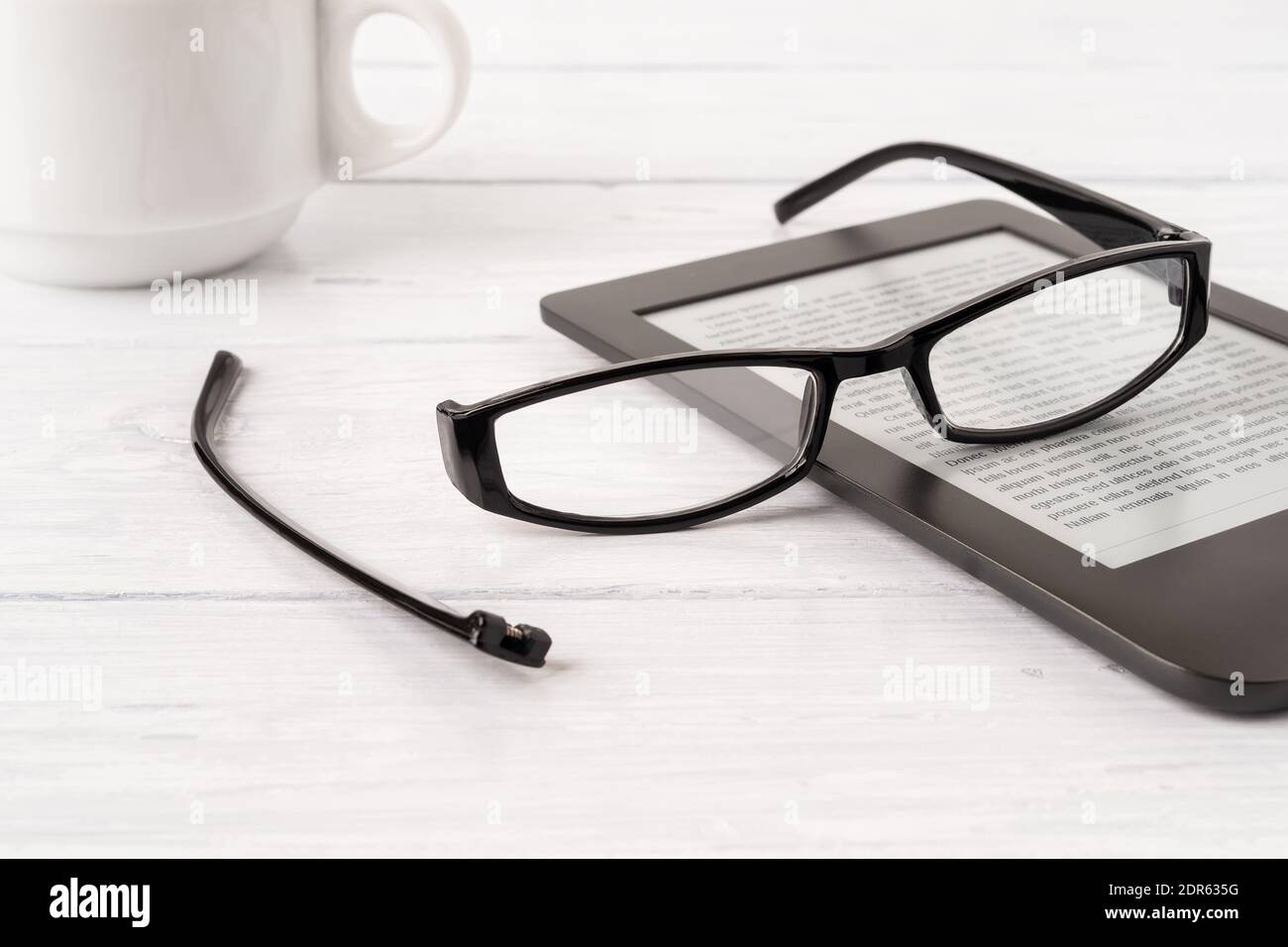 Brillen mit einem Bügel, der vom Rand auf einem E-Reader über einem  Schreibtisch aus weißem Holz gebrochen wurde. Bruch der Sehkorrekturbrille  zum Lesen Stockfotografie - Alamy