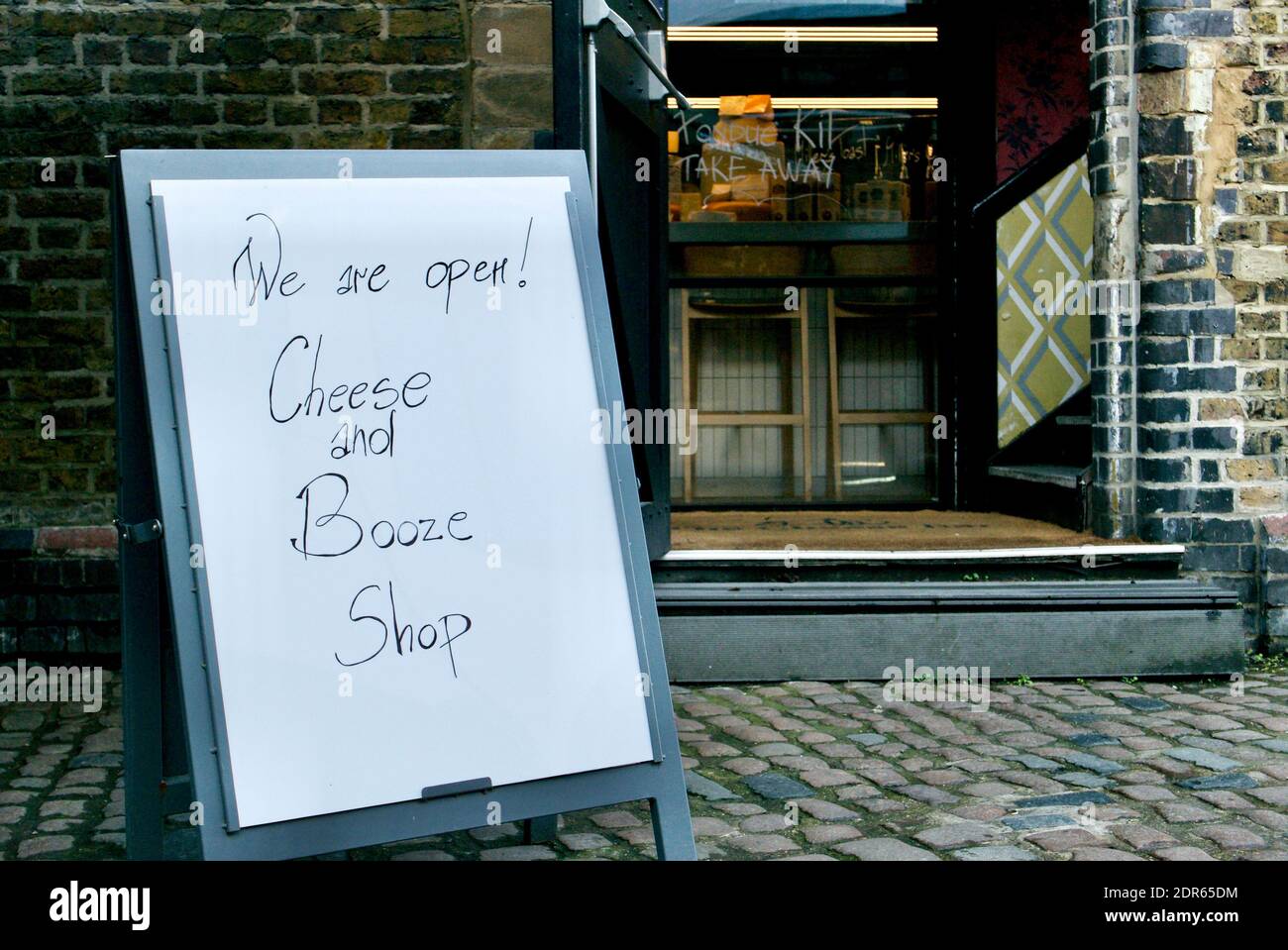 Wir sind offen Schild vor einem Käse und Alkohol (Alkohol) Shop in Camden am ersten Tag der Tier 4 covid Einschränkungen. Shop ist leer von Kunden. London Stockfoto