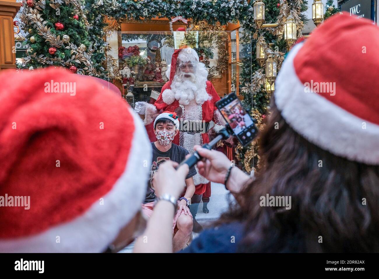 Menschen mit Gesichtsmasken fotografieren mit dem Weihnachtsmann im Pavillion Einkaufszentrum in Kuala Lumpur. Stockfoto