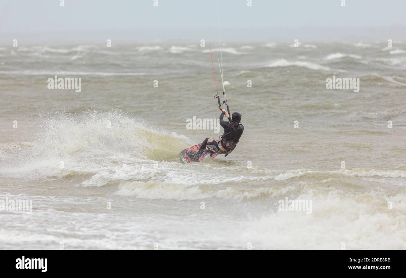 Ein Kiteboarder, der an einem regnerischen Tag auf den Wellen im Meer reitet. Boundary Bay, BC, Kanada-November 17,2020. Selektiver Fokus, Sportfoto, Reisefoto. Stockfoto