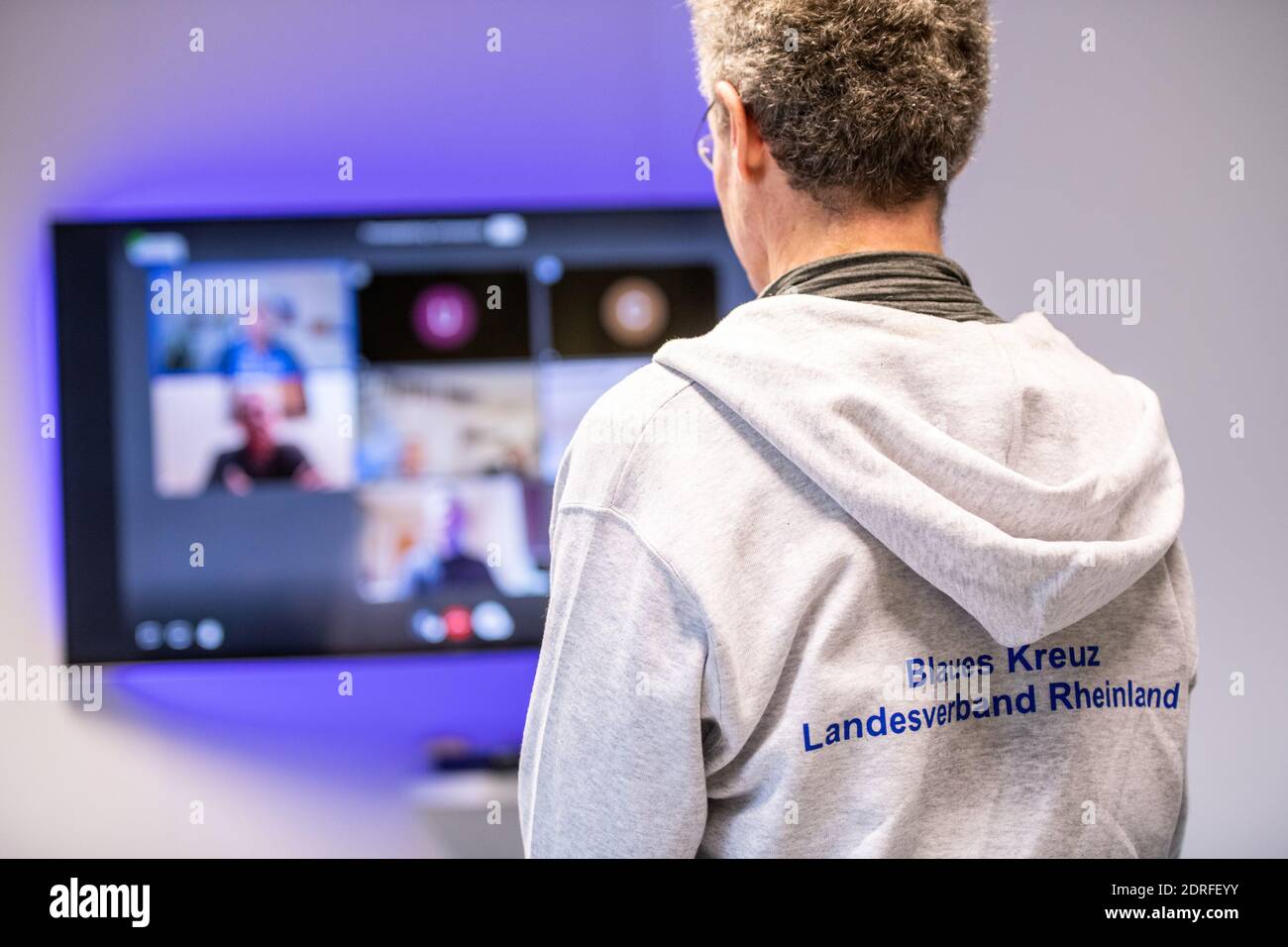 30. November 2020, Nordrhein-Westfalen, Remscheid: Michael Buchner, Gruppenleiter Blaues Kreuz Deutschland e.V., steht vor einer Leinwand mit einem Videotreffen. In Nordrhein-Westfalen waren Gruppenversammlungen nahezu universell möglich, da nach Ziffer 7 der Corona-Schutzverordnung Selbsthilfeangebote zu den "weiteren außerschulischen Bildungsangeboten" gehören. Dennoch haben die Gruppen der Suchtselbsthilfe derzeit auch andere kommunikative Wege vielerorts genutzt und nutzen sie noch. Vom Telefon, zum Walk-in-Pairs, Whats-App-Gruppen, Chats oder Videokonferenzen. (t Stockfoto