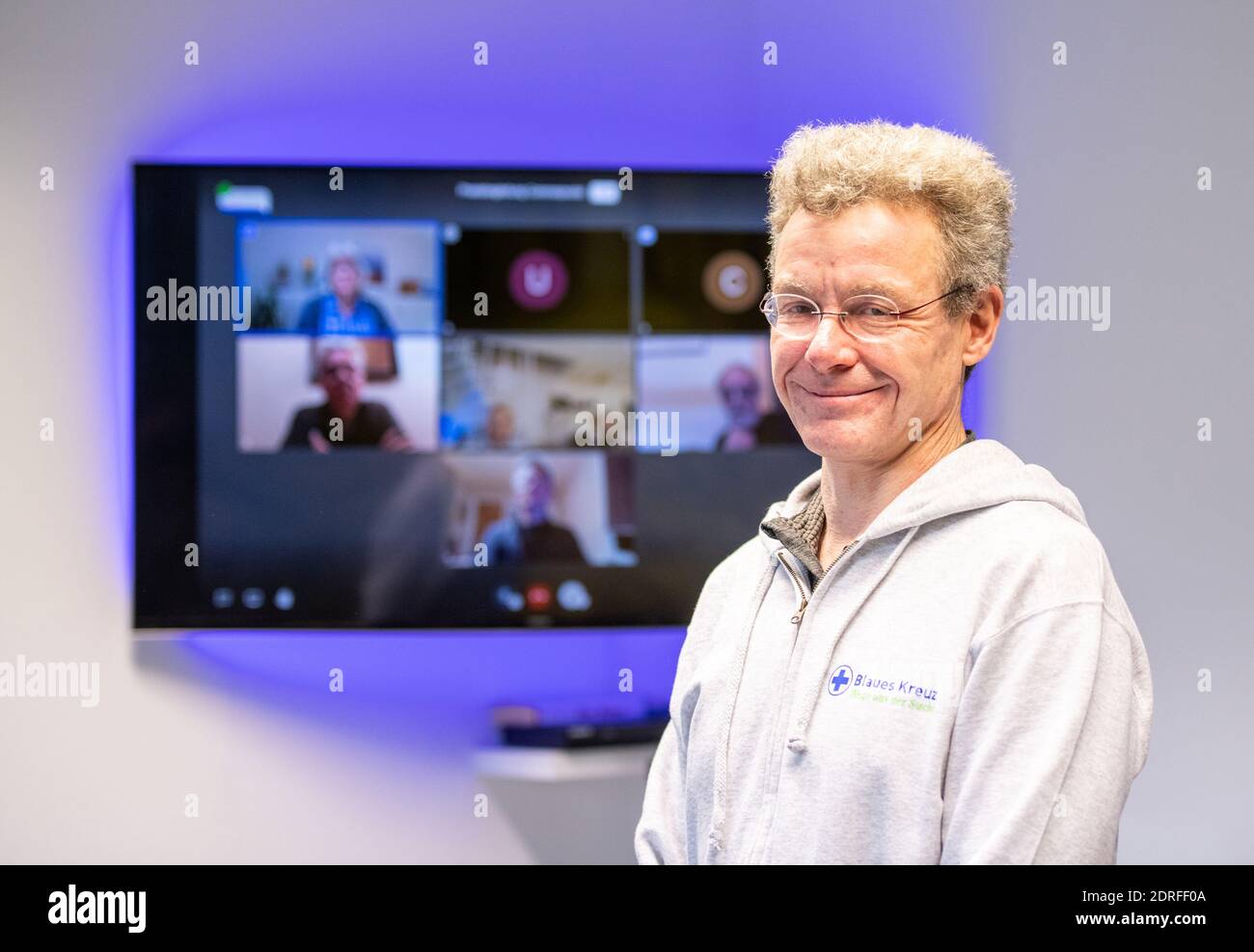 30. November 2020, Nordrhein-Westfalen, Remscheid: Michael Buchner, Gruppenleiter Blaues Kreuz Deutschland e.V., steht vor einer Leinwand mit einem Videotreffen. In Nordrhein-Westfalen waren Gruppenversammlungen nahezu universell möglich, da nach Ziffer 7 der Corona-Schutzverordnung Selbsthilfeangebote zu den "weiteren außerschulischen Bildungsangeboten" gehören. Dennoch haben die Gruppen der Suchtselbsthilfe derzeit auch andere kommunikative Wege vielerorts genutzt und nutzen sie noch. Vom Telefon, zum Walk-in-Pairs, Whats-App-Gruppen, Chats oder Videokonferenzen. (t Stockfoto