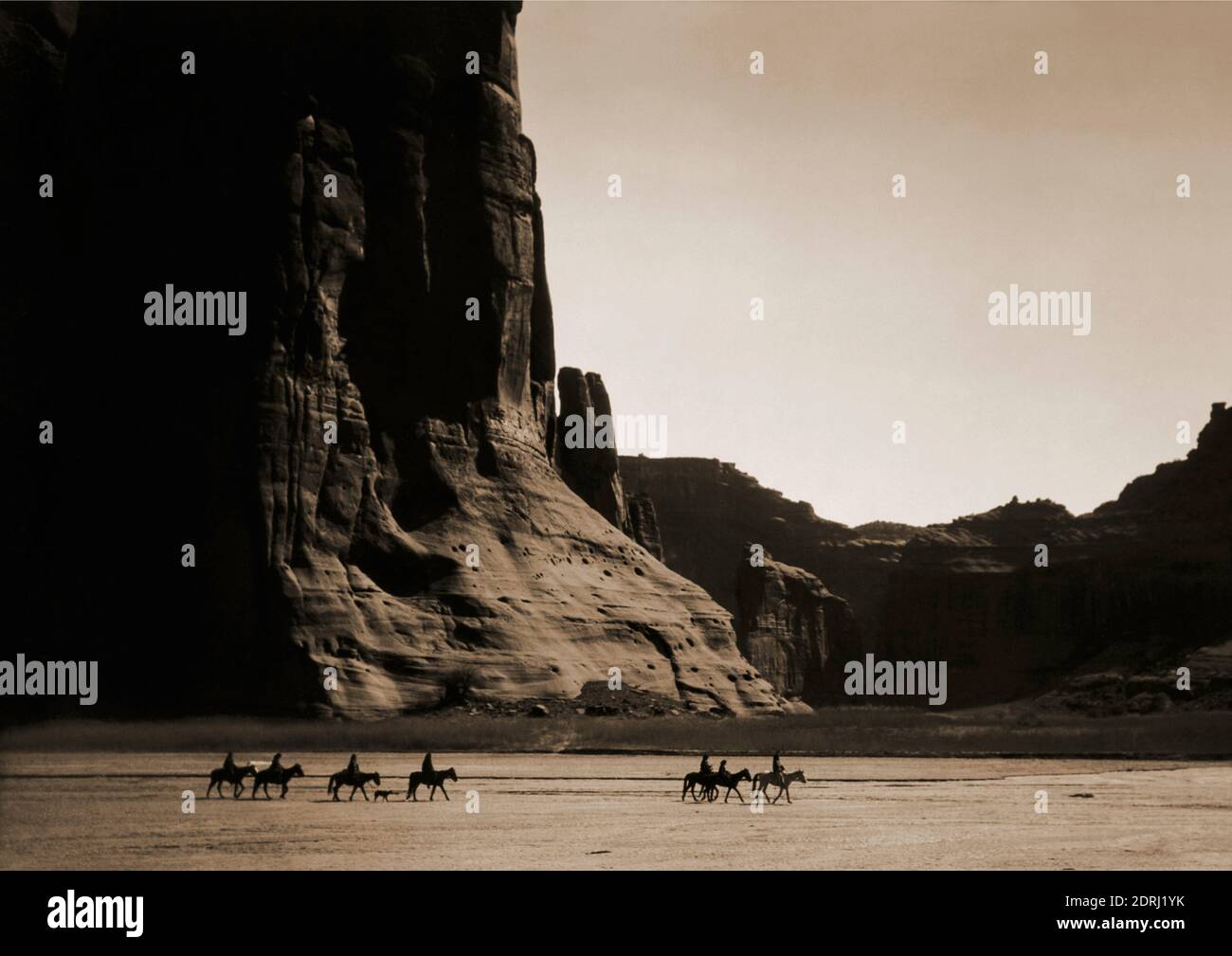 Vintage-Foto von 1904 von Edward S Curtis von sieben Reitern auf dem Pferd und Hund Trekking vor dem Hintergrund der Canyon Klippen. Canyon De Chelly. Stockfoto