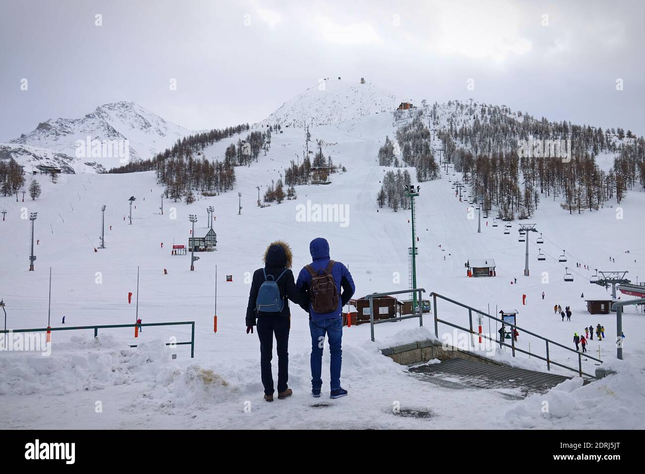 Skipisten wegen Pandemie über Weihnachten geschlossen, Paar schaut auf trostlos leere Pisten. Sestriere, Italien - Dezember 2020 Stockfoto