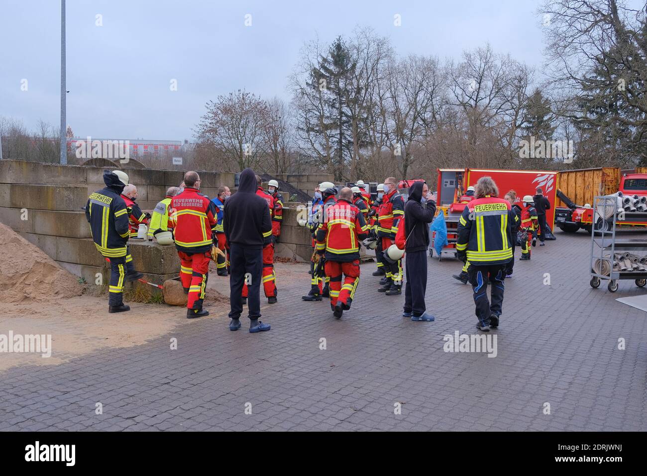 Bad Segeberg, Deutschland. Dezember 2020. Feuerwehrleute stehen bei einem Treffen auf dem Gelände des Wegezweckverbandes. Hier brannte am frühen Morgen ein Fahrzeug, so dass das Feuer auch in einem Lagerhaus ausbrach. Die Feuerwehr löschte das Fahrzeug, das in Brand geraten war. Die Brandursache ist noch unklar. In der Halle des Abfallwirtschaftsunternehmens wurden Spezialfahrzeuge und -Material gelagert. Kredit: Frank Molter/dpa/Alamy Live Nachrichten Stockfoto