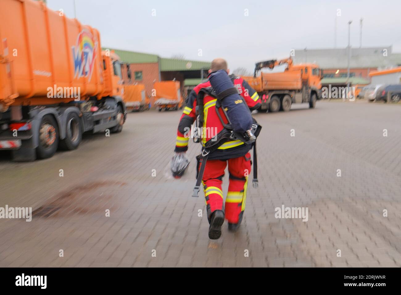 Bad Segeberg, Deutschland. Dezember 2020. Ein Feuerwehrmann geht über das Gelände des Wegezweckverbandes. Hier brannte am frühen Morgen ein Fahrzeug, so dass das Feuer auch in einem Lagerhaus ausbrach. Die Feuerwehrleute löschten das Fahrzeug, das in Brand geriet. Die Brandursache ist noch unklar. In der Halle des Abfallwirtschaftsunternehmens wurden Spezialfahrzeuge und -Material gelagert. Kredit: Frank Molter/dpa/Alamy Live Nachrichten Stockfoto