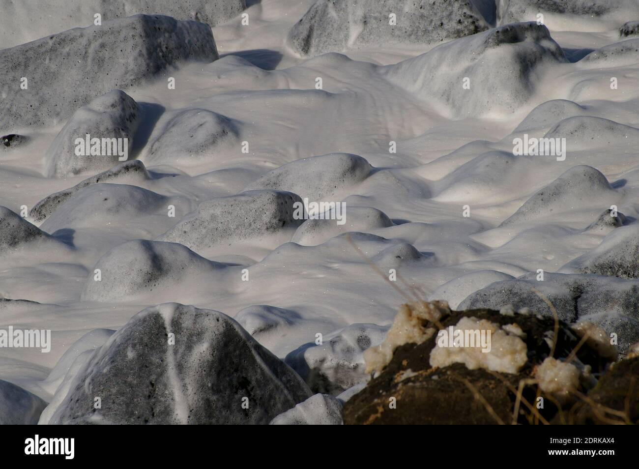 Kleine Wellen, die nach einem Sturm an der Gold Coast in Australien mit Schaum bedeckt waren. Schaum bildet sich, wenn Salz und frisches Wasser zusammenwirken. Platz kopieren, Hintergrund. Stockfoto