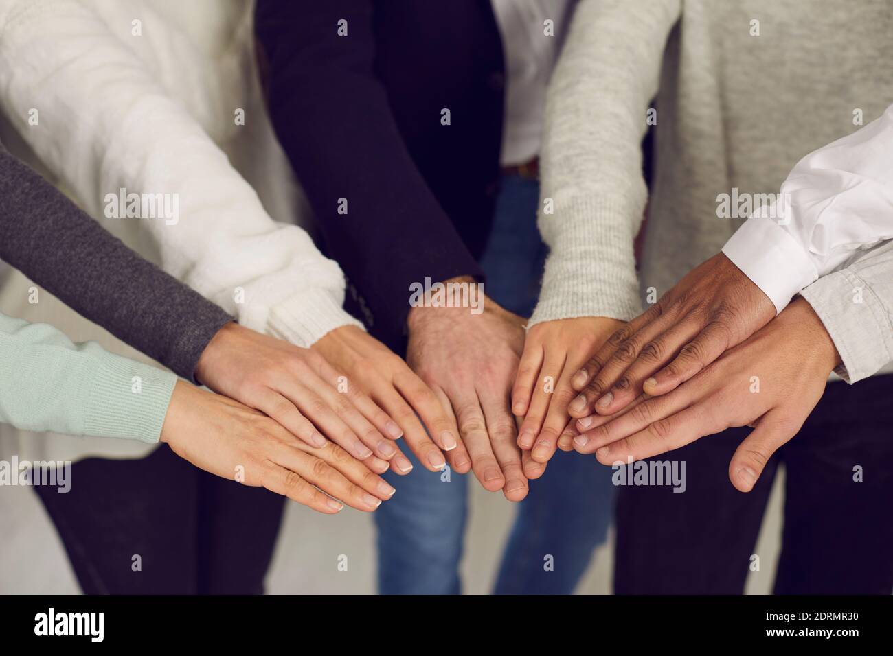 Gruppe von Menschen, die sich die Hände als Symbol für Teamgeist, Einheit und gegenseitige Unterstützung verbinden Stockfoto