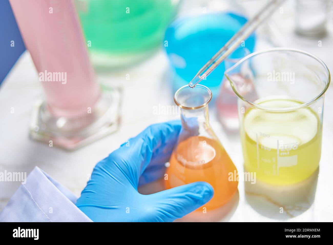 Labortechniker mit blauen Handschuhen, die Experimente und Tests in durchführen Ein Labor mit verschiedenfarbigen Substanzen Stockfoto