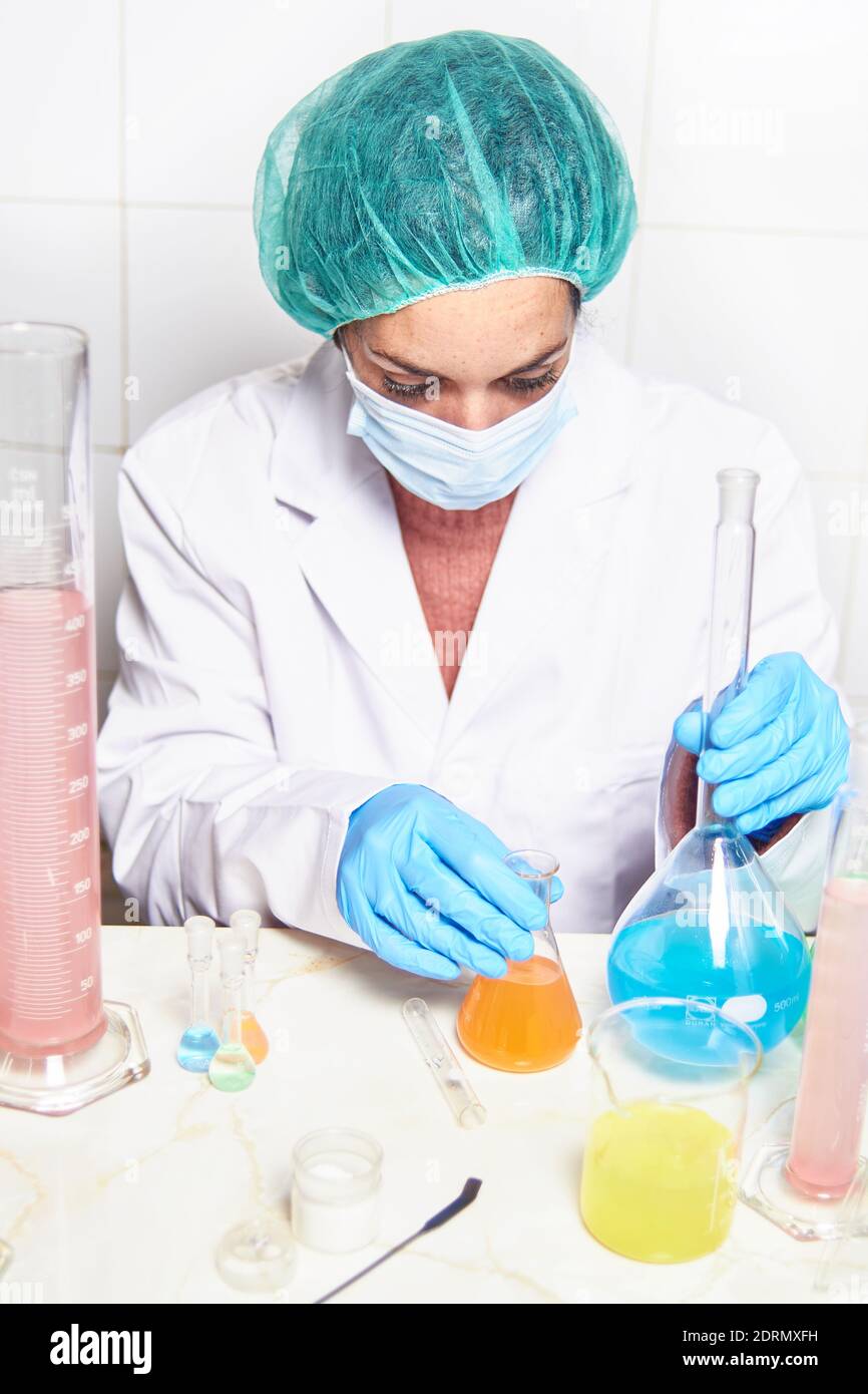 Wissenschaftliche Ärztin mit Handschuhen, Gesichtsmaske und Laborkittel, die an der Forschung und Durchführung von Experimenten im Labor arbeitet Stockfoto