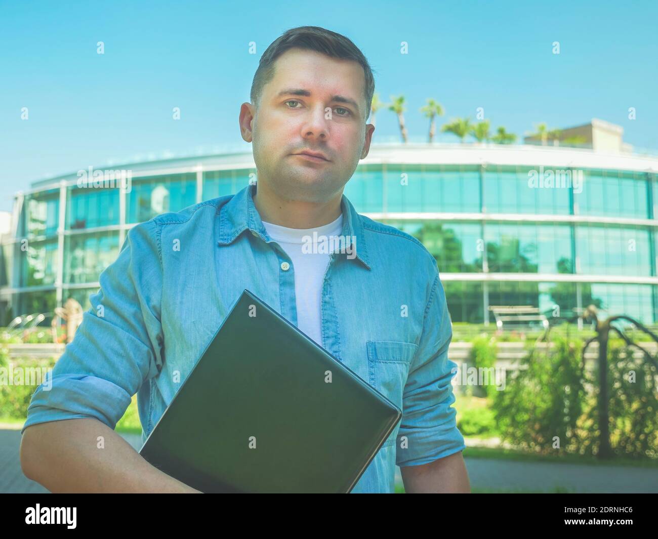 Porträt eines jungen attraktiven Mann mit einem Laptop im Sommer auf der Straße. Stockfoto