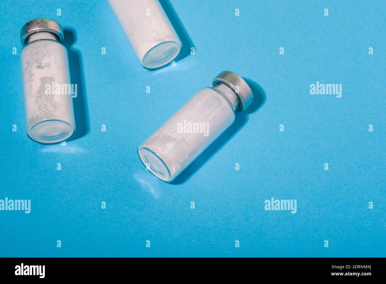 Coronavirus-Impfstoff. Glasflasche. Neue Medikamente von Covid. Ampulle auf blauem Hintergrund Nahaufnahme Stockfoto