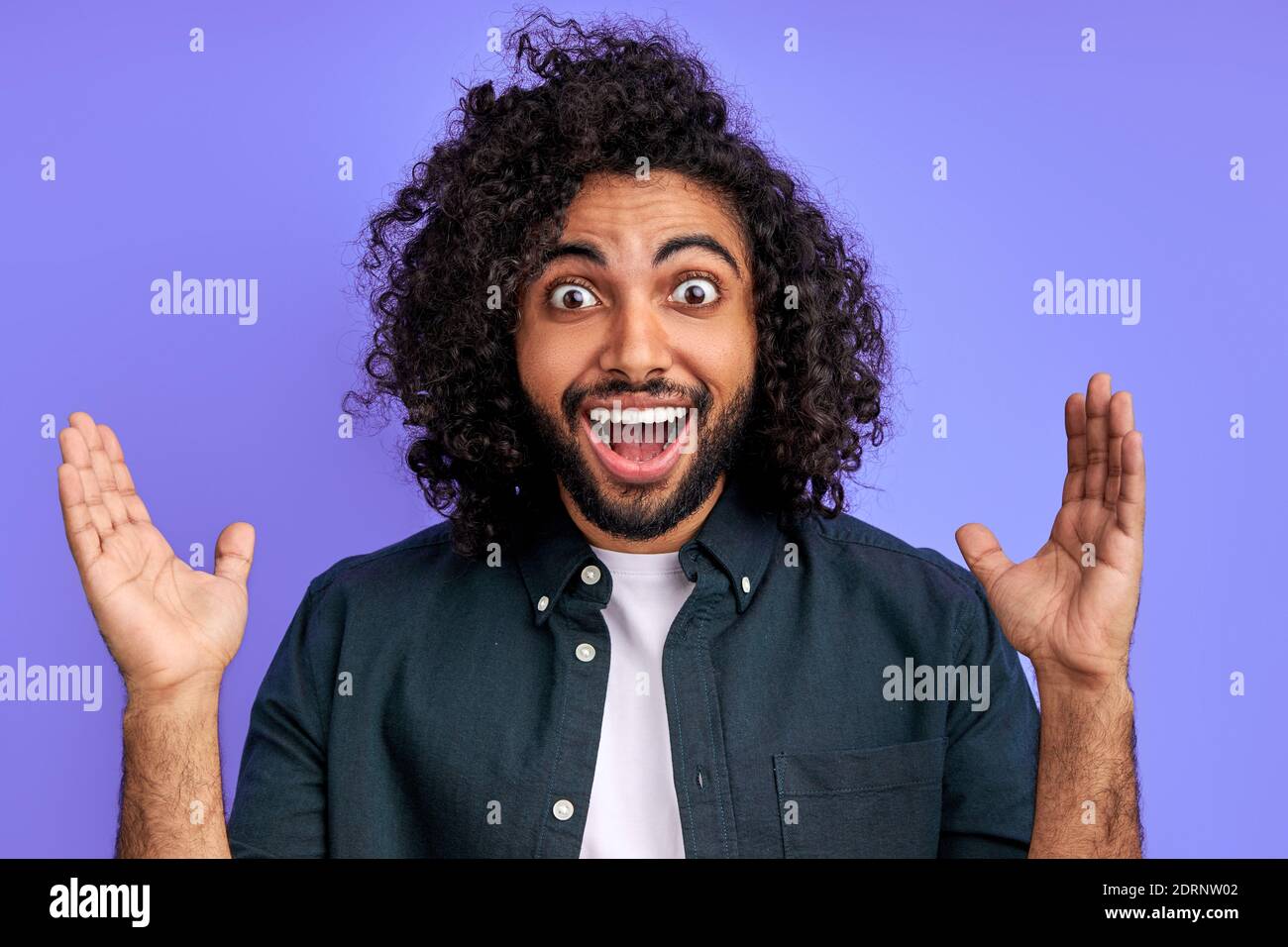 Der junge arabische Mann ist von etwas überrascht, er reagiert emotional auf etwas, auf Nachrichten. Mann schaut mit geöffnetem Mund und großen Augen glücklich in die Kamera. Stockfoto