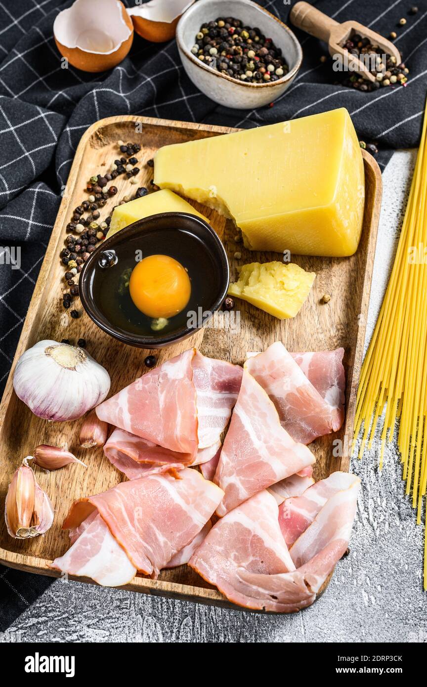 Traditionelle Italienische Pasta Carbonara Zutaten. Speck, Spaghetti, Parmesan und Pecorino Käse, Ei, Knoblauch. Grauer Hintergrund. Draufsicht. Stockfoto