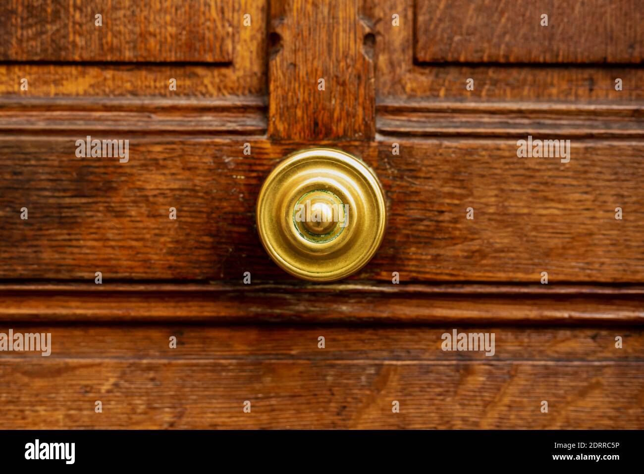 Alter runder Türgriff an alter brauner Holztür. Nahaufnahme Paris, Frankreich. Goldene Messingdetails an alter Holztür. Griff auf braunem altem Holz schäbig Stockfoto