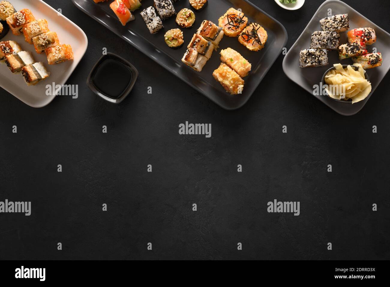 Asiatische Küche mit Sushi-Set auf schwarzem Hintergrund. Blick von oben. Flach liegend. Lieferung von Lebensmitteln. Stockfoto