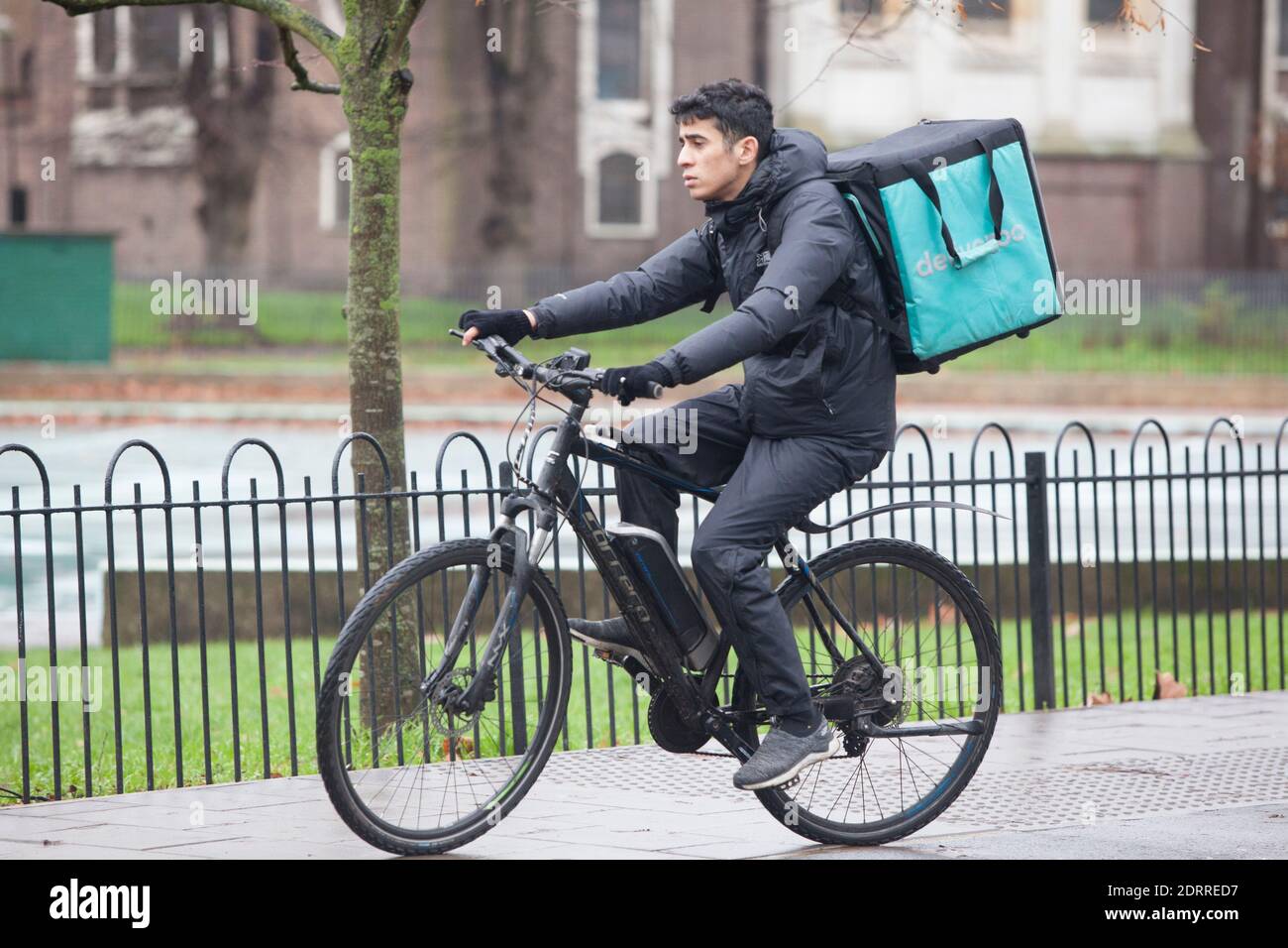 Clapham, London, 21. Dezember 2020: Im Regen stehen die Leute Schlange, um Weihnachtsaufträge von einem lokalen Metzger zu sammeln. Unter Tier 4 Coronavirus Einschränkungen sollten die Menschen zu Hause bleiben, außer für wesentliche Einkäufe und zur Arbeit zu gehen. Cafés und Restaurants sind nur für Essen zum Mitnehmen geöffnet und Deliveroo liefert Lebensmittel sowie warme Mahlzeiten. Anna Watson/Alamy Live News Stockfoto