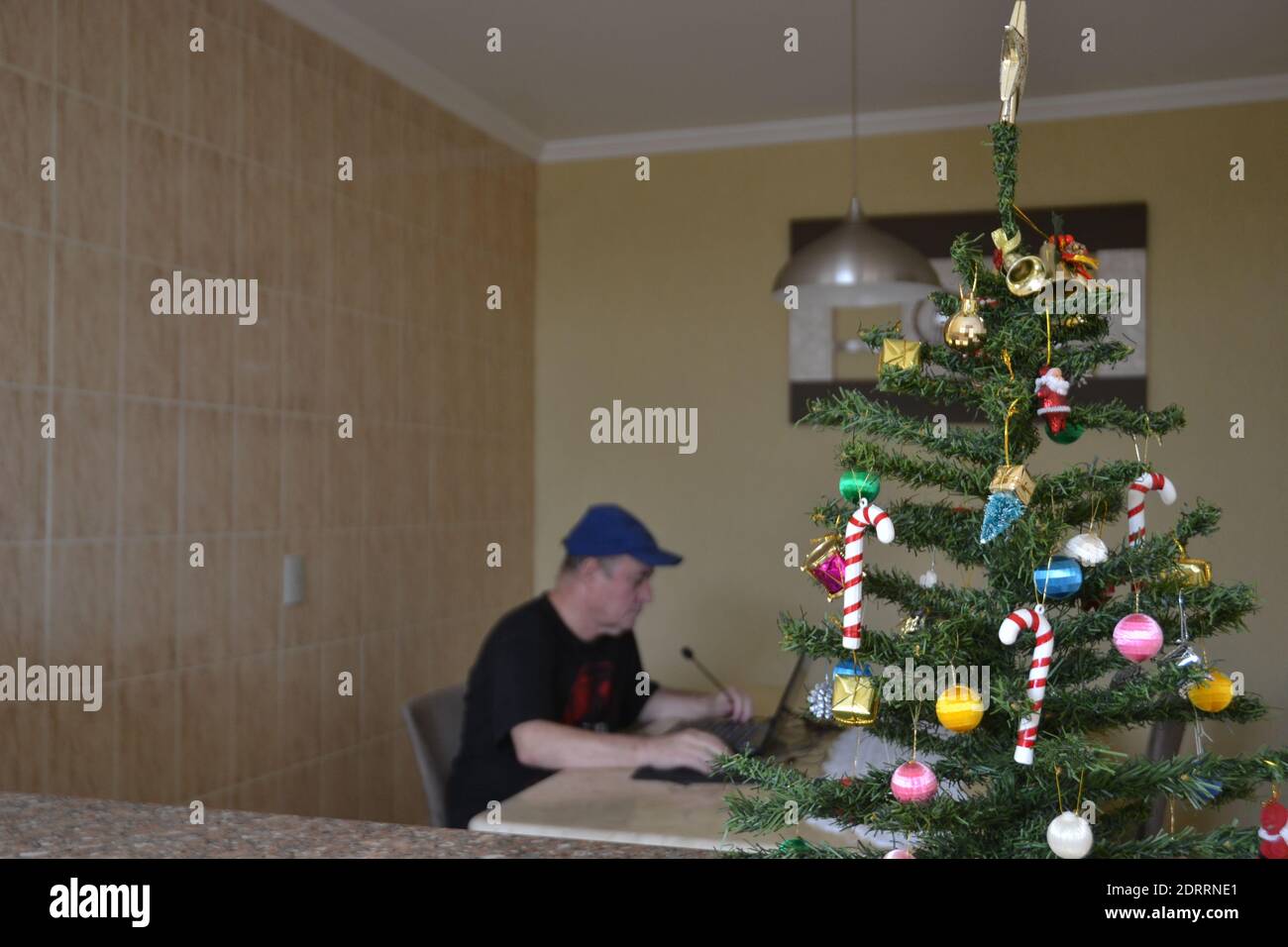 Älterer Mann. Zur Weihnachtszeit Teilnahme an Online-Treffen auf Notebook im Home Office in Brasilien auf Marmortisch, Fotografie mit Fokus auf Christma Stockfoto