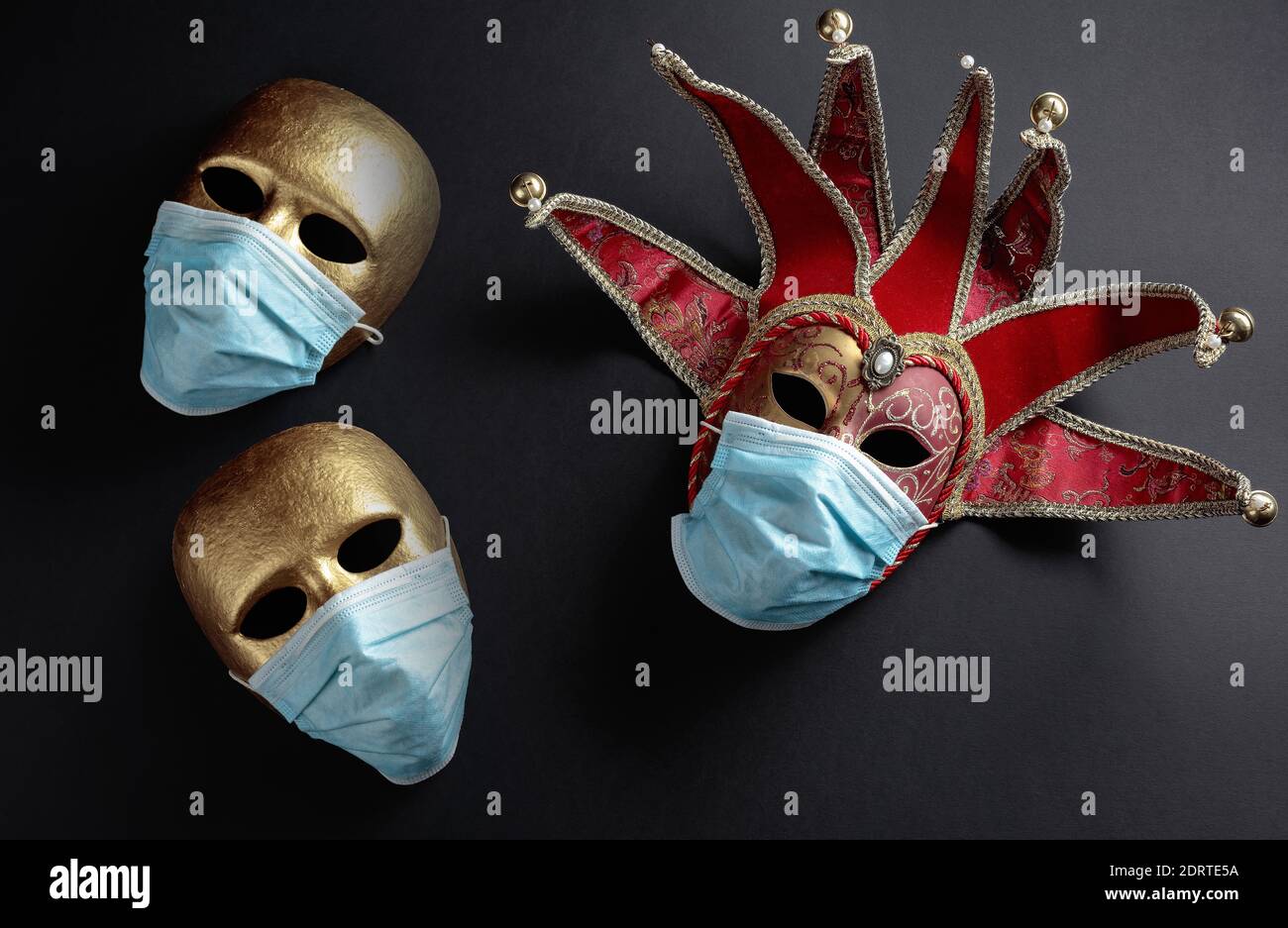 Karnevalsmasken in Schutzmasken. Konzeptuelles Bild des Themas des Virus. Speicherplatz kopieren. Stockfoto