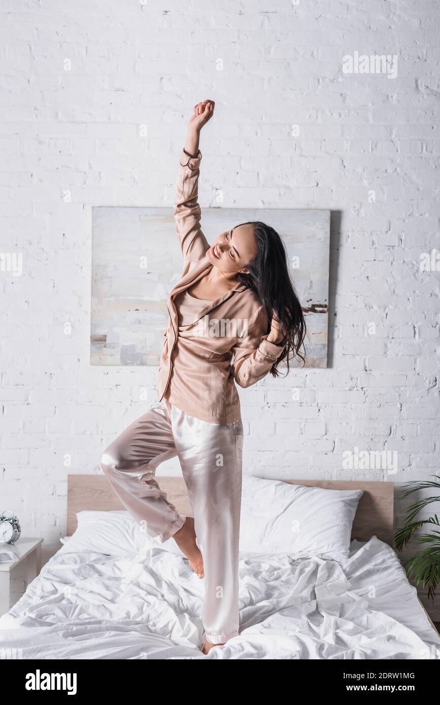 Junge Brünette Frau tanzen im Bett am Morgen Stockfoto