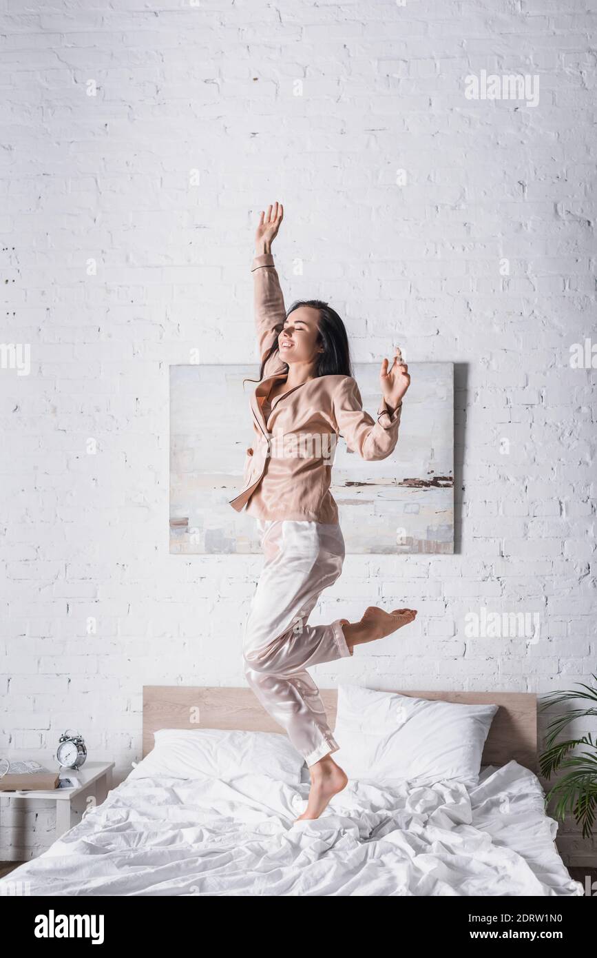 Junge Brünette Frau springen im Bett am Morgen Stockfoto