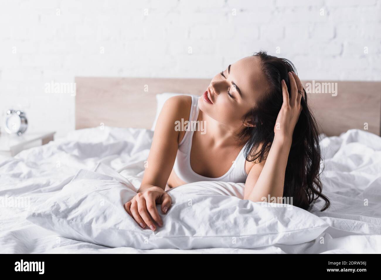 Junge Brünette Frau im Bett mit geschlossenen Augen Stockfoto