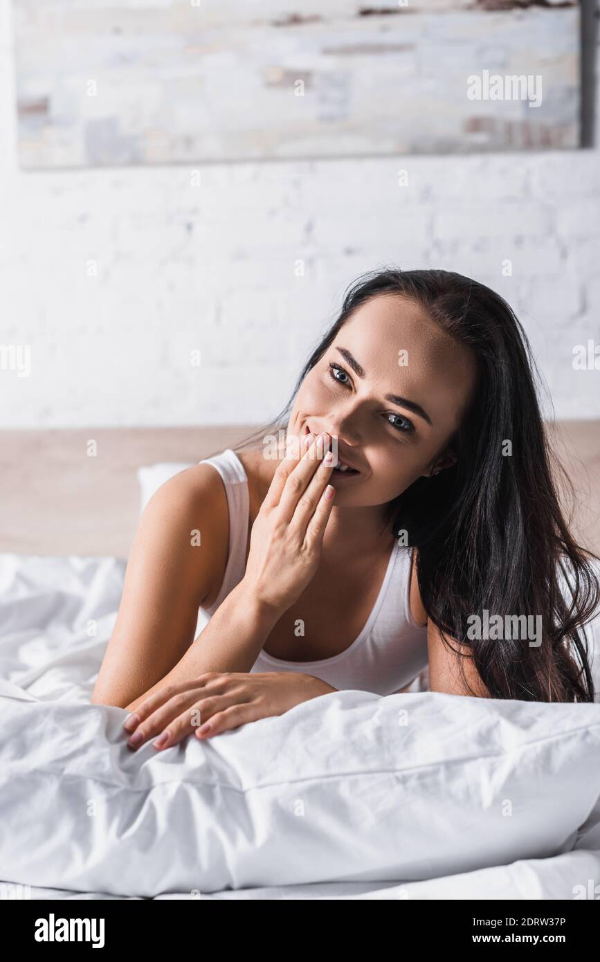 Lächelnd junge Brünette Frau im Bett Stockfoto