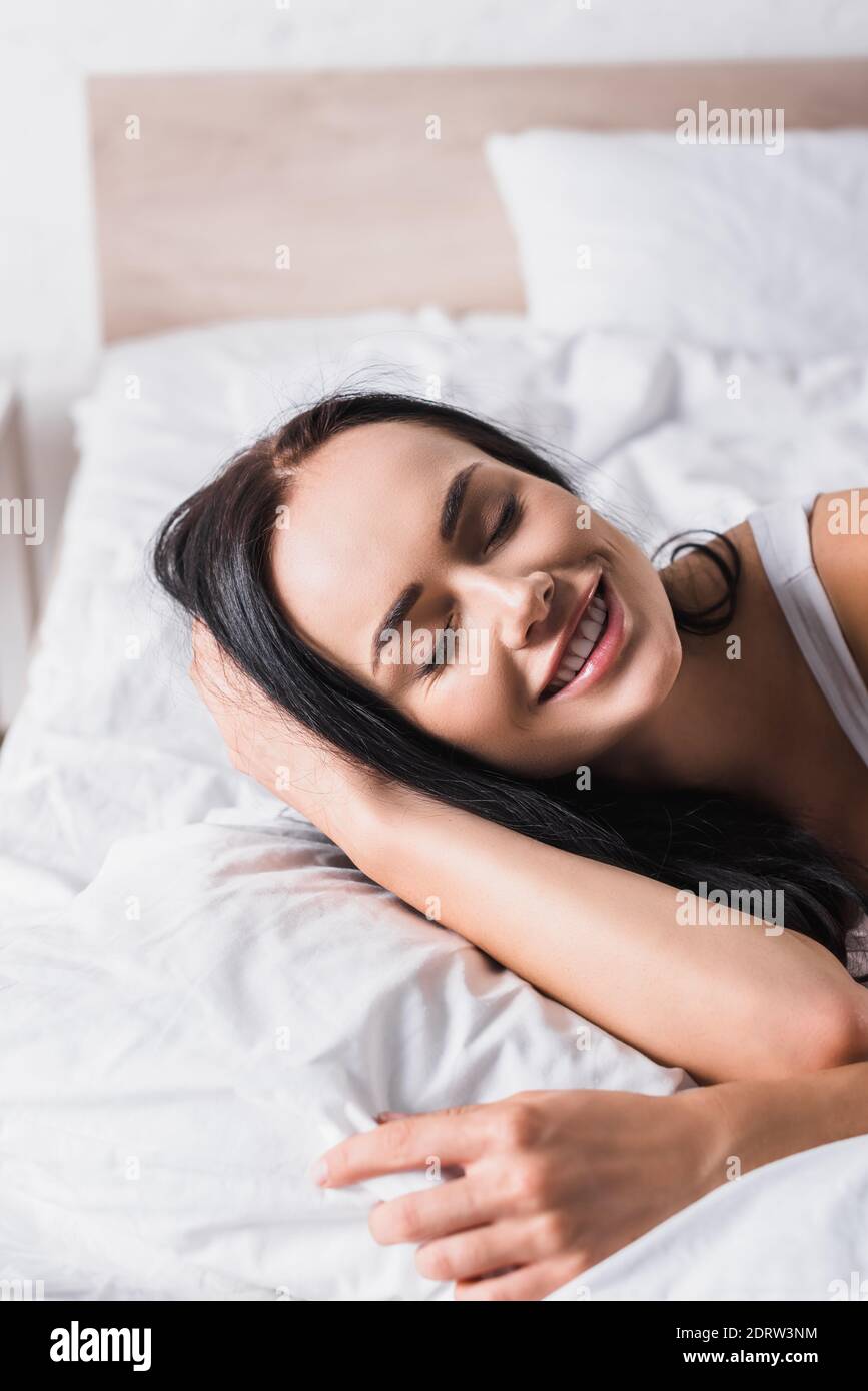 Lächelnd junge Brünette Frau im Bett Stockfoto