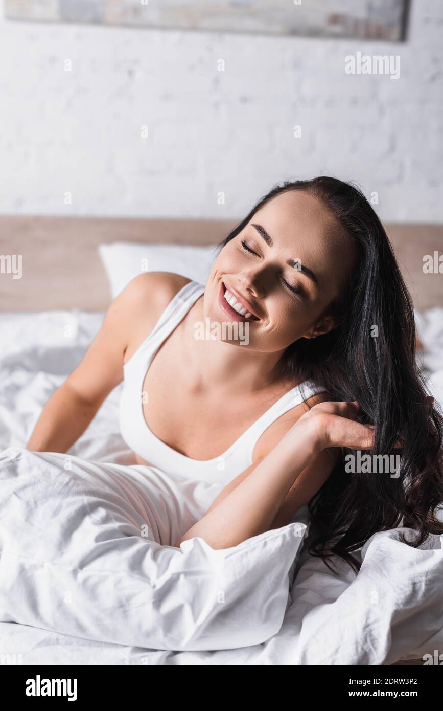 Glücklich junge Brünette Frau im Bett Stockfoto