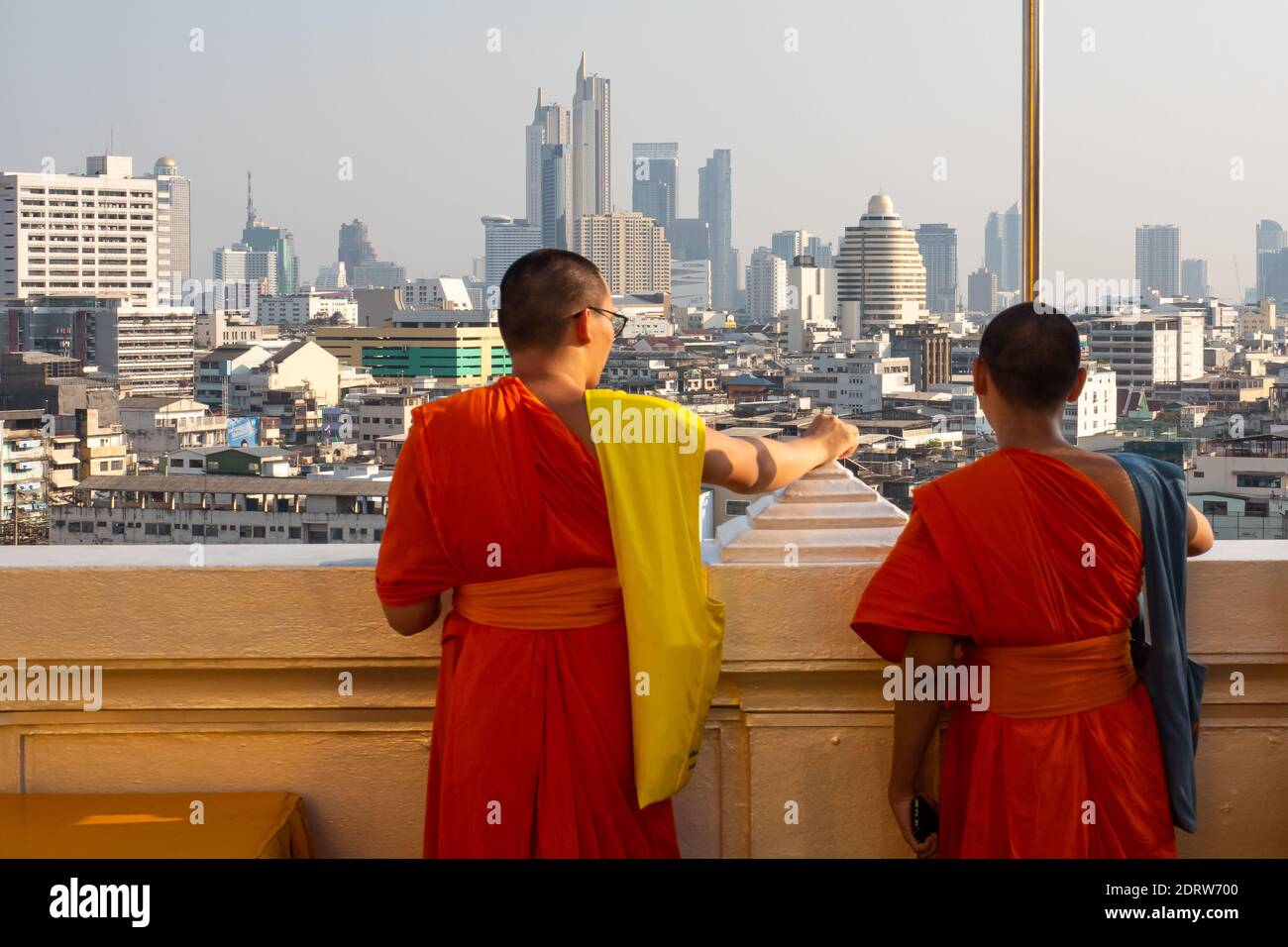 Zwei buddhistische Mönche in roten Gewändern blicken auf die Skyline des modernen Bangkok-Baus. Thailand 2019 Stockfoto