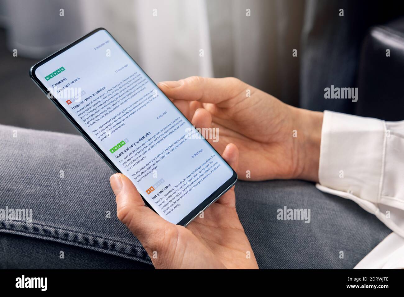 Frau, die Telefon benutzt, um Kundenbewertungen über Service und zu lesen Produktqualität vor dem Online-Shopping Stockfoto