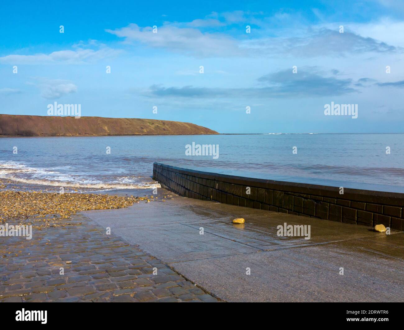 Wellen und die Promenade bei Flut am Strand In Filey ein beliebter Badeort im Norden von Yorkshire Küste in Nordengland Großbritannien Stockfoto