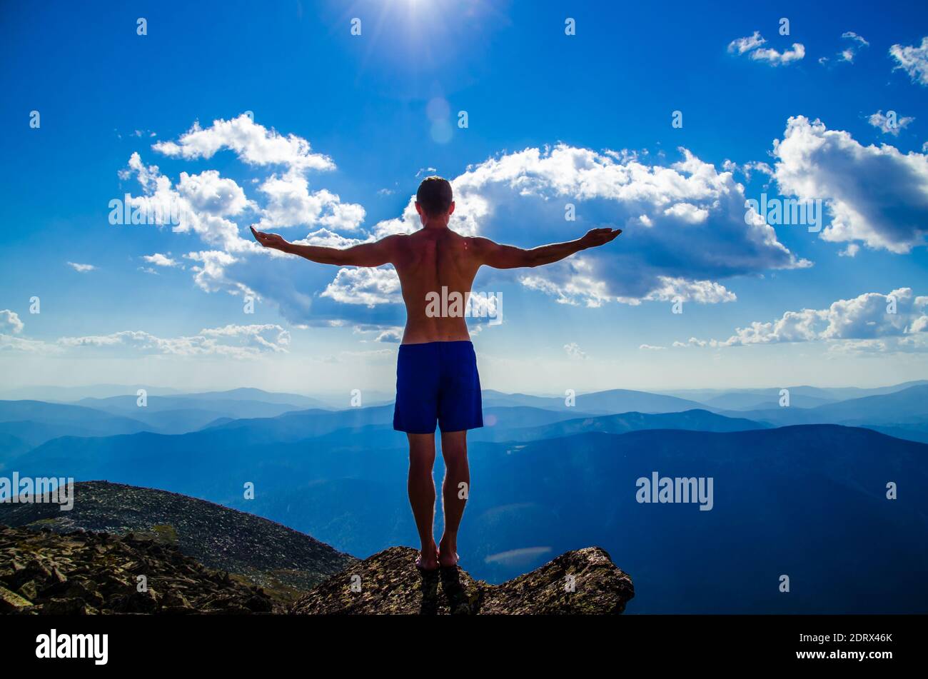 Der Mensch steht auf einem Berg mit offenen Händen. Oben auf dem Berg ist ein Mann mit weit ausgebreiteten Armen. Stockfoto