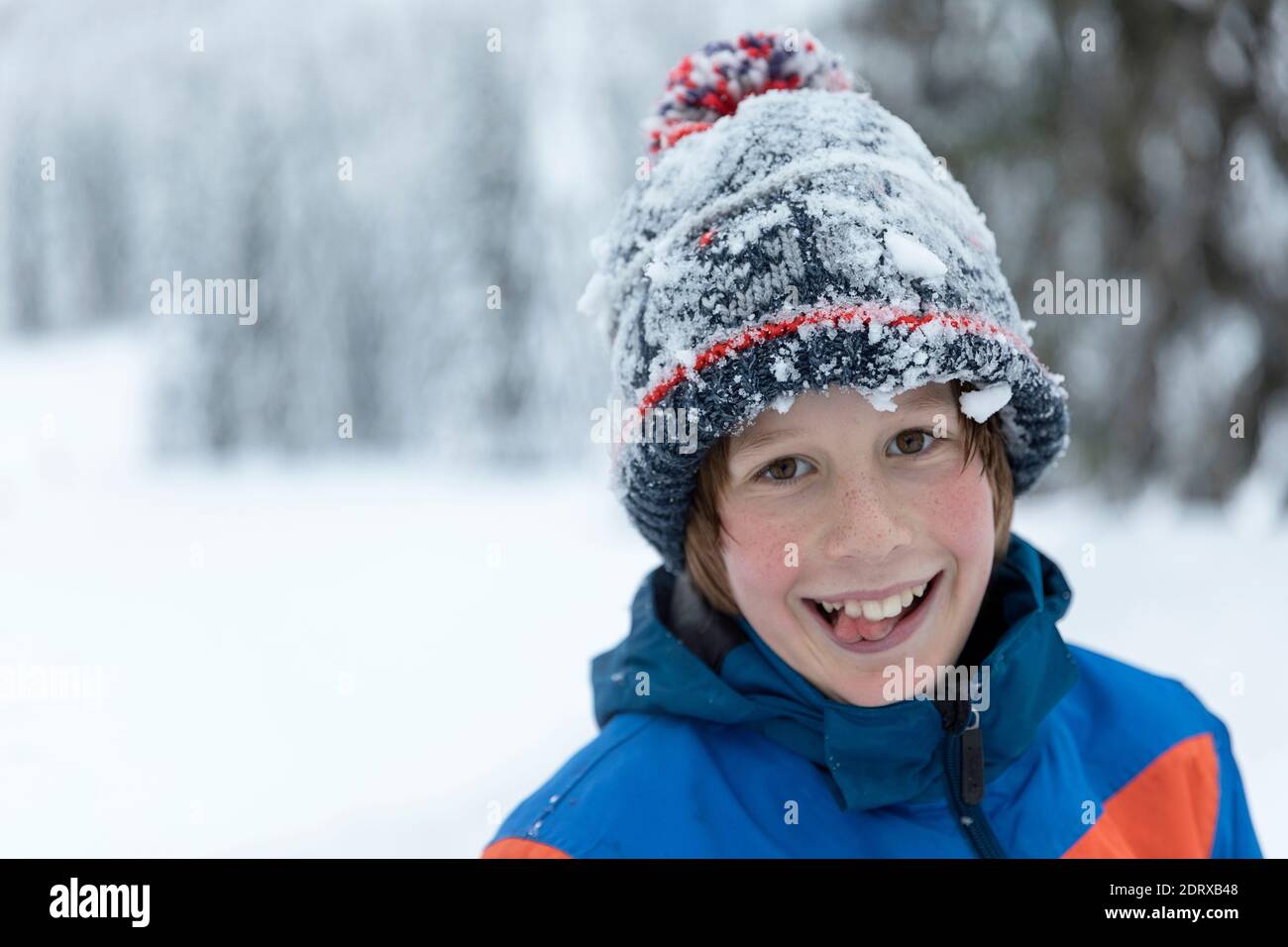 Wintertag, Porträt von niedlichen glücklichen Jungen mit einer Mütze mit Schnee bedeckt Stockfoto