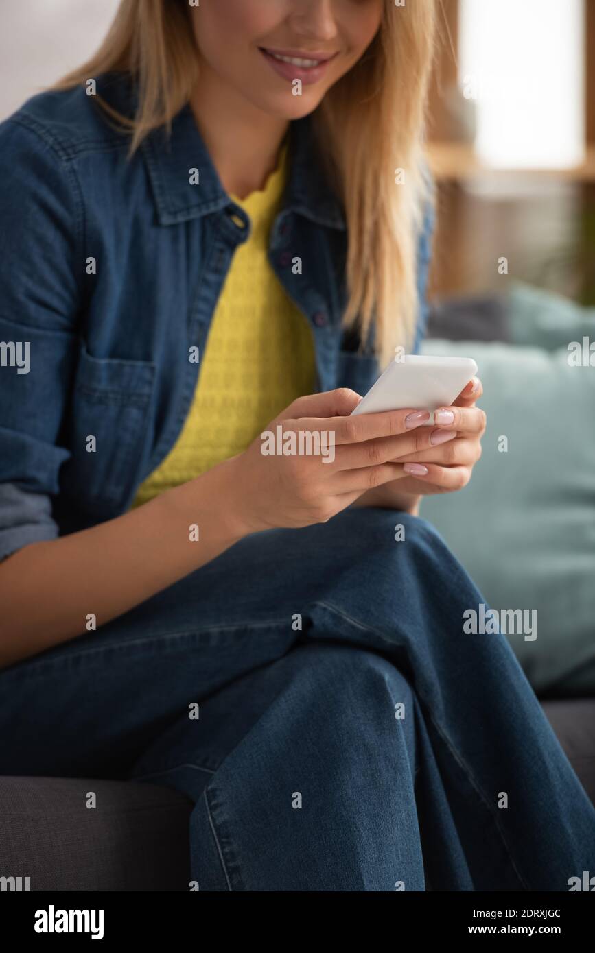 Beschnittene Ansicht der jungen Frau SMS auf Smartphone auf verschwommen Hintergrund Stockfoto