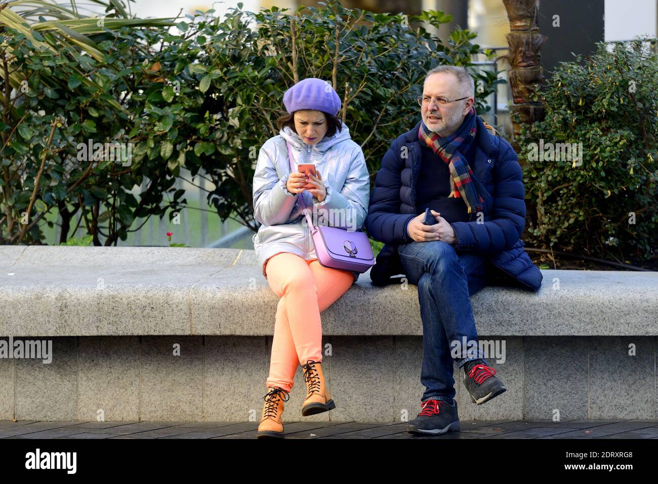 London, England, Großbritannien. Frau trägt leuchtend orange / Pfirsich Leggings und Turnschuhe, auf ihrem Handy in Leicester Square Stockfoto