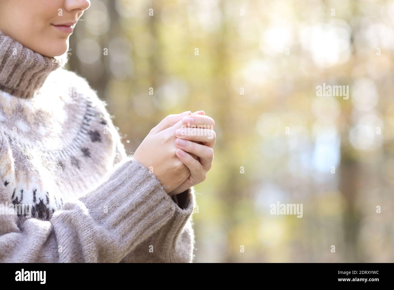 Nahaufnahme einer Frau, die in einem kalten Winter die Hände erhitzt In einem Park Stockfoto