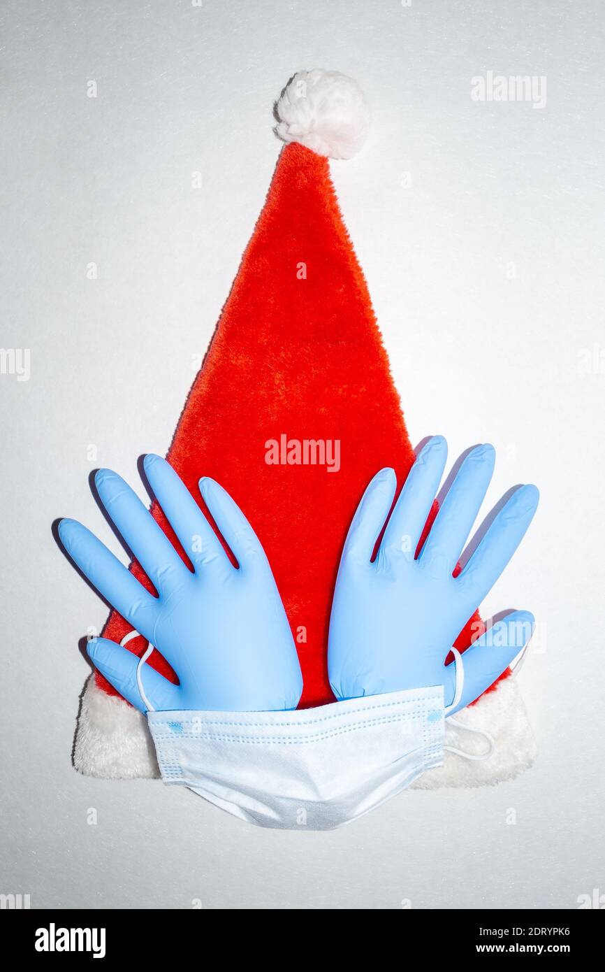 Weihnachtsmann Hut mit OP-Maske und ein Paar aufgeblasene blaue medizinische Vinyl-Handschuhe. Draufsicht Stockfoto