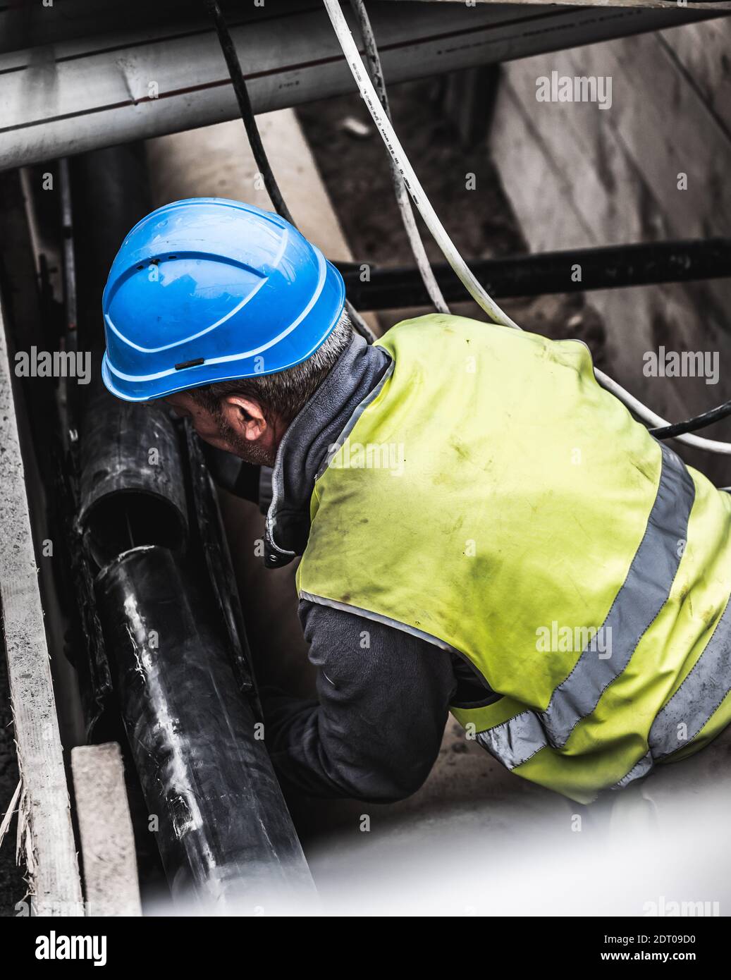 Rohrmonteur in gelber Uniform auf einer Baustelle arbeiten. Arbeiter, die  Rohre unterirdisch montieren, Genf, Schweiz Stockfotografie - Alamy