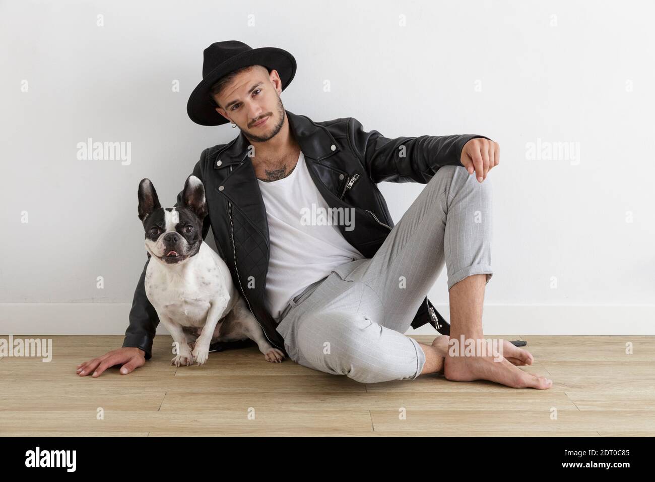 Hipster Junge mit Lederjacke und Hut neben seinem Haustier, ein französischer Bulldogge Hund auf weißem Hintergrund Stockfoto