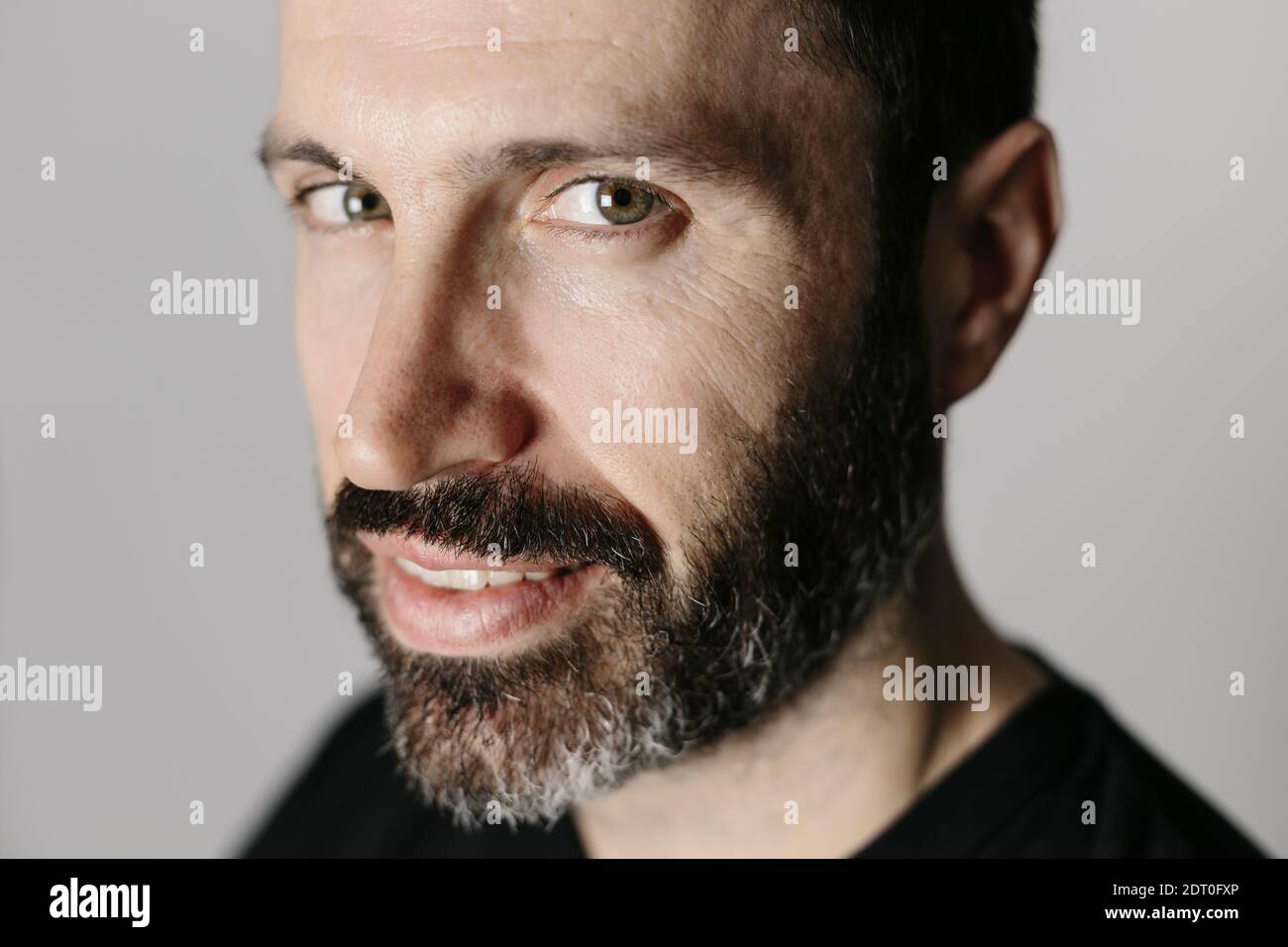 Nahaufnahme eines hübschen bärtigen Mannes mittleren Alters gegen Neutral Hintergrund Stockfoto