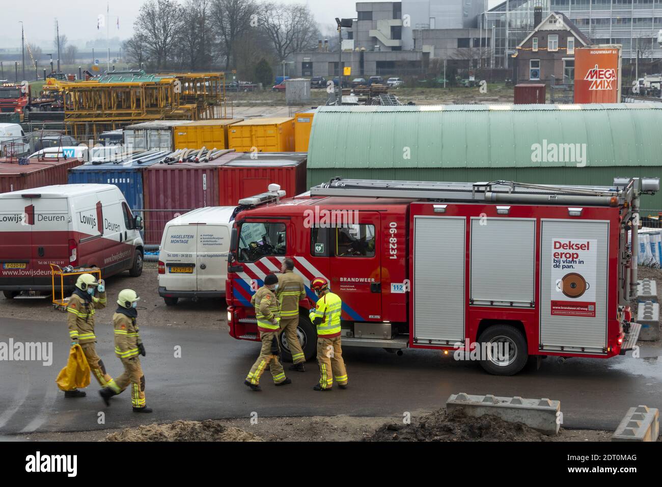 ZUTPHEN, NIEDERLANDE - 08. Dez 2020: LKW- und Feuerwehrleute auf einer Baustelle, die zu ihrem Fahrzeug zurückkehren Stockfoto