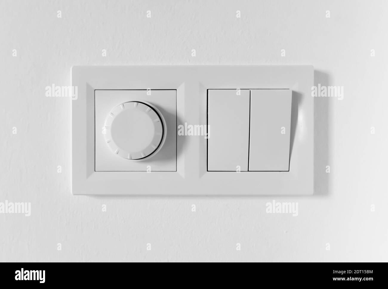 Paar einfache Lichtschalter mit Dimmer. Preiswerter mechanischer Doppelschalter aus Kunststoff mit Thermostat gegen weiße Wand. Alte Klimaanlage Stockfoto