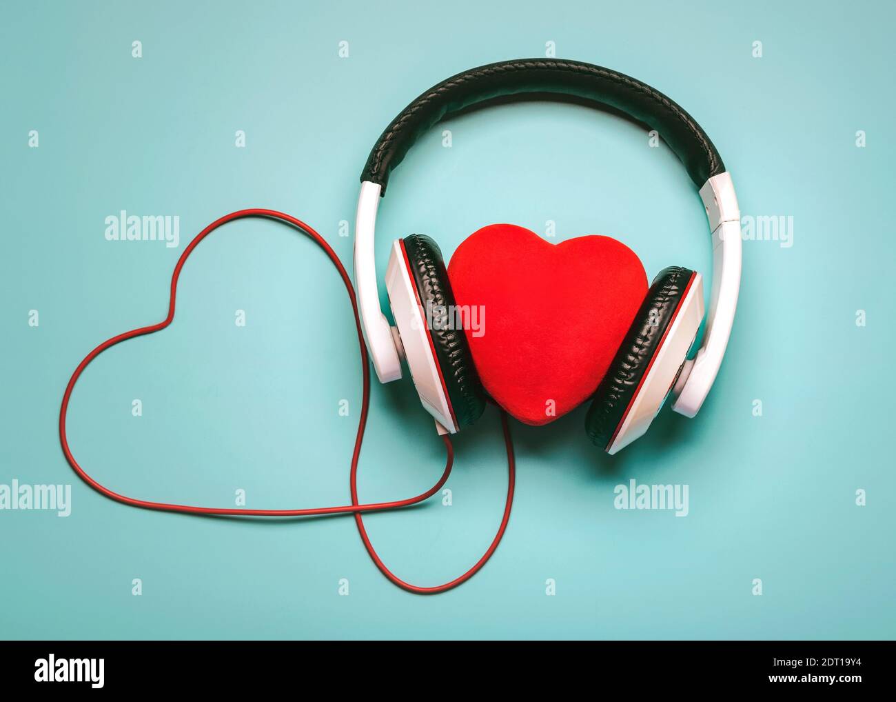 Herz mit Kopfhörern und rotem Herz-förmigen aufklappbar auf einem blauen Hintergrund.Romantisches Musikkonzept Stockfoto