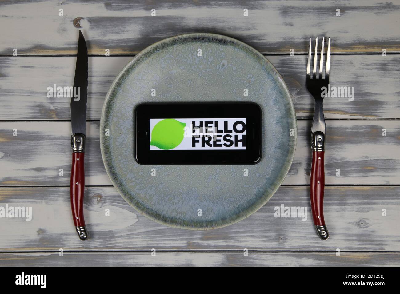 Viersen, Deutschland - 9. Mai. 2020: Nahaufnahme des Handybildschirms mit Logo-Schriftzug des Food Delivery Service hellofresh auf Holztisch mit Schale und Cu Stockfoto