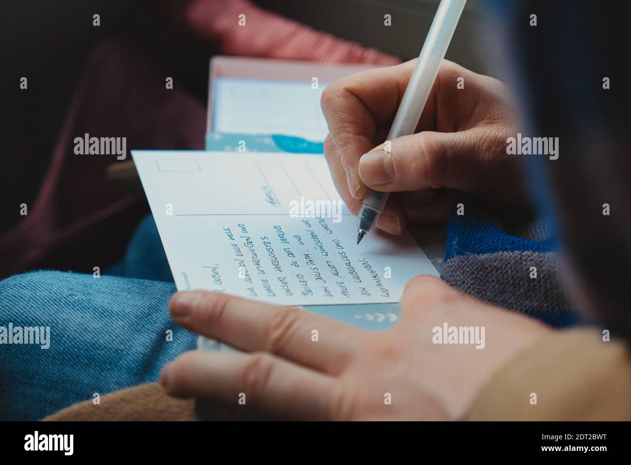 Hand der Person, die Postkarte mit Stift füllt. Nahaufnahme. Stockfoto