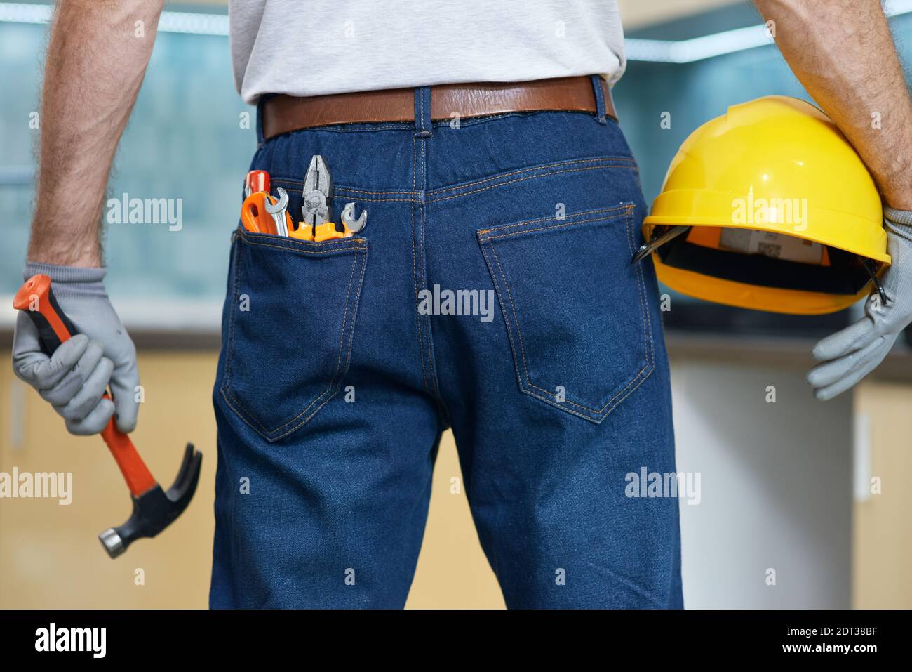Nahaufnahme von verschiedenen Sanitär-Handwerkzeuge in der Jeans Gesäßtasche des Mannes. Professionelle Werkstatt hält einen Hammer und einen Helm in den Händen Stockfoto